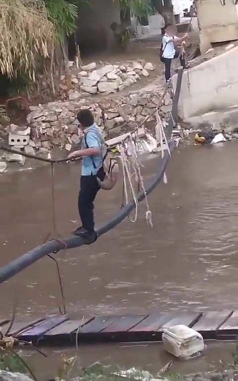 Niños haciendo equilibrios sobre una cuerda para cruzar un río lleno de cocodrilos e ir al colegio