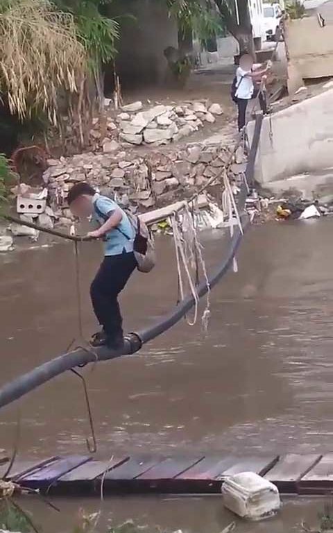 Niños haciendo equilibrios sobre una cuerda para cruzar un río lleno de cocodrilos e ir al colegio