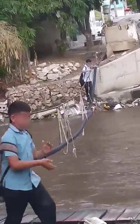 Niños haciendo equilibrios sobre una cuerda para cruzar un río lleno de cocodrilos e ir al colegio