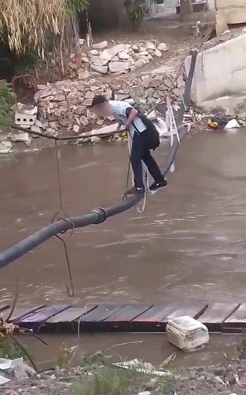 Niños haciendo equilibrios sobre una cuerda para cruzar un río lleno de cocodrilos e ir al colegio