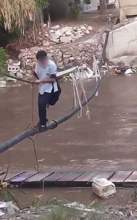 Niños haciendo equilibrios sobre una cuerda para cruzar un río lleno de cocodrilos e ir al colegio